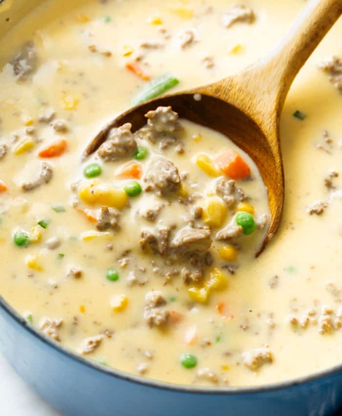A wooden spoon scooping Shepherd's Pie Soup from a soup pot.