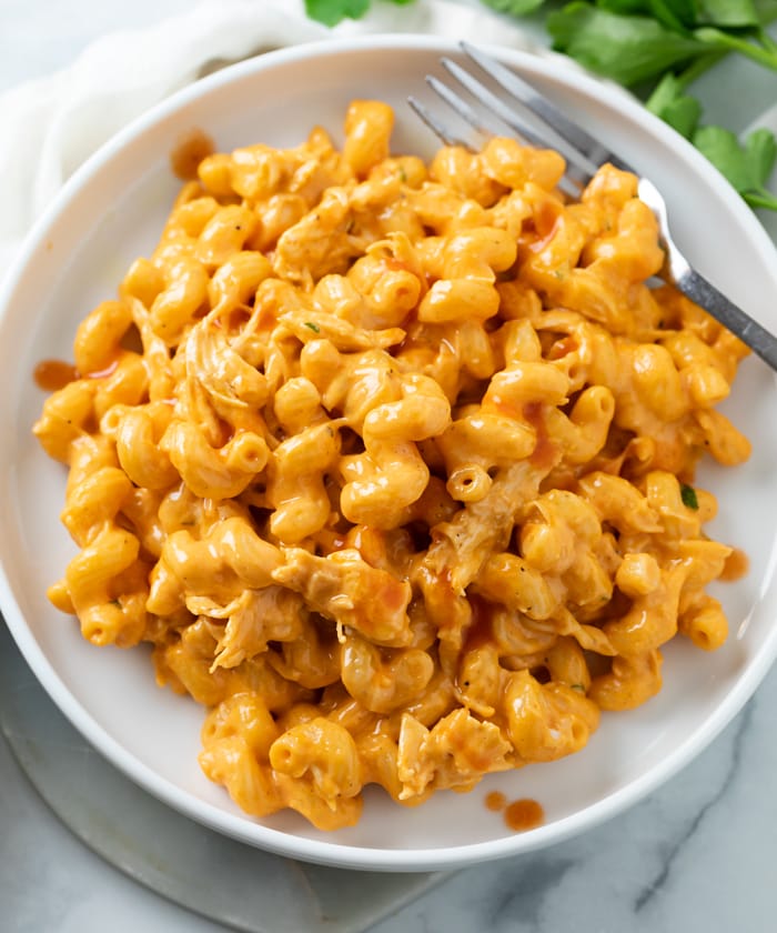 A white plate with Buffalo Chicken Mac and Cheese and a fork on the side.