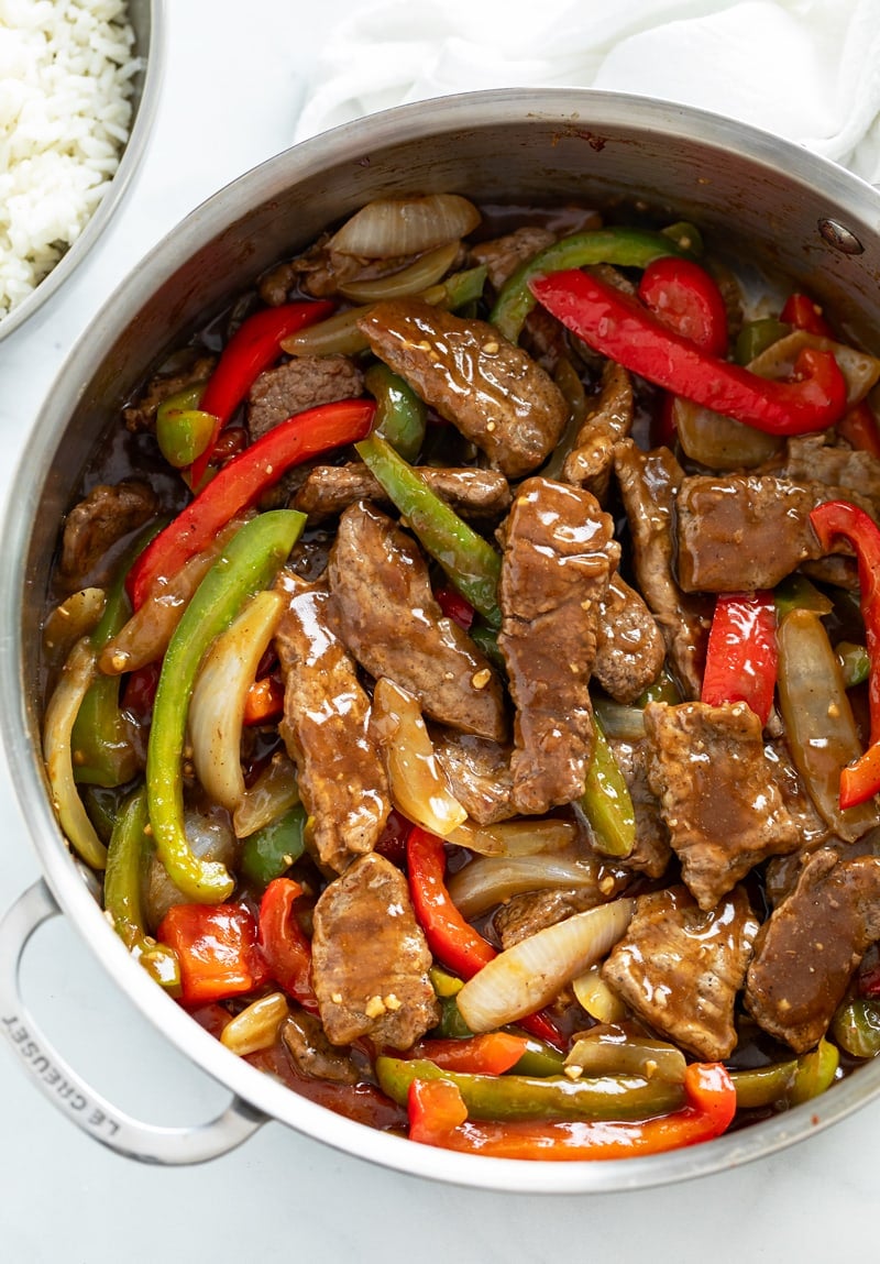 A skillet filled with Pepper Steak in a brown sauce with onions and peppers.