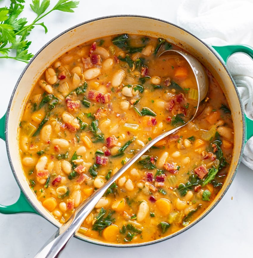 A soup pot with White Bean Soup with a ladle.