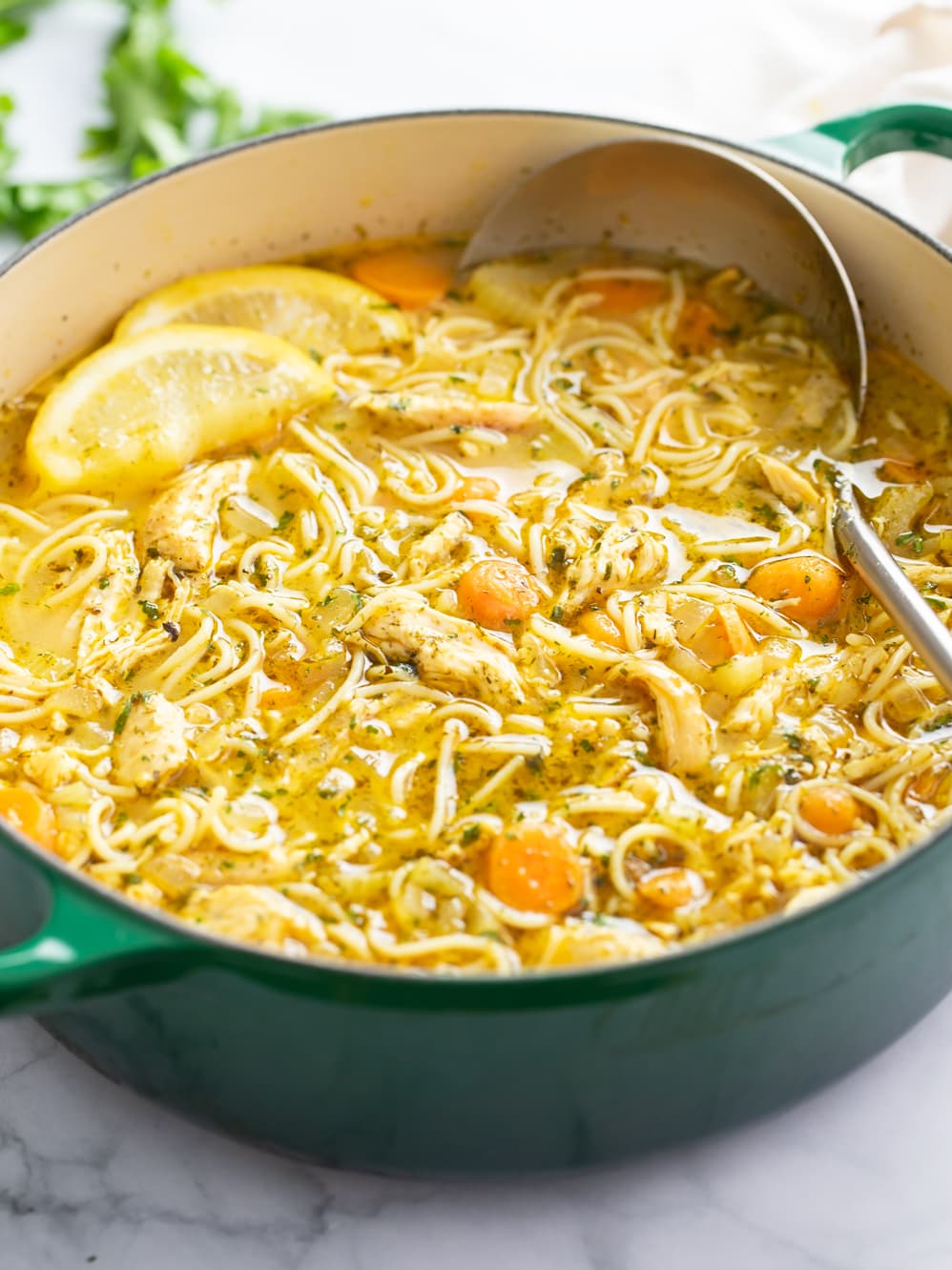 Lemon Chicken Soup in a green soup pot with lemons on top.