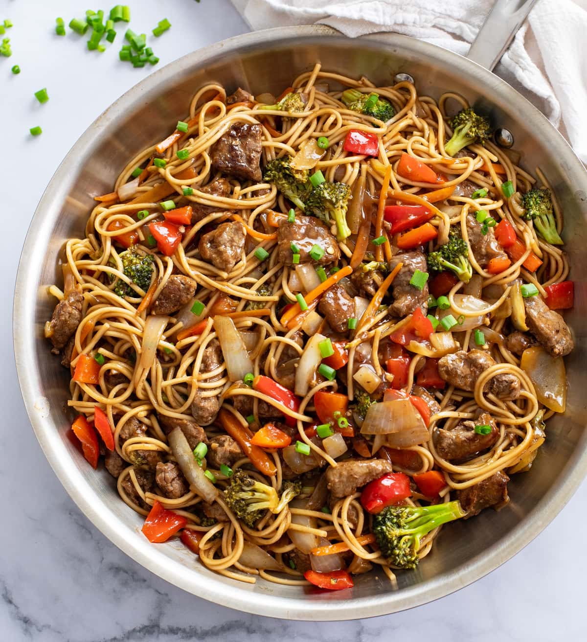 Beef Lo Mein in a skillet with vegetables and brown sauce.