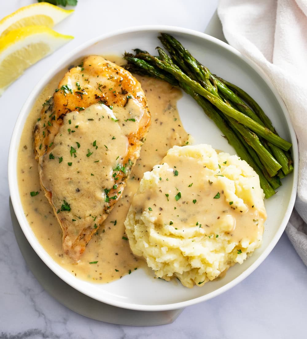 Garlic Parmesan Pasta on a white plate with mashed potatoes and asparagus.