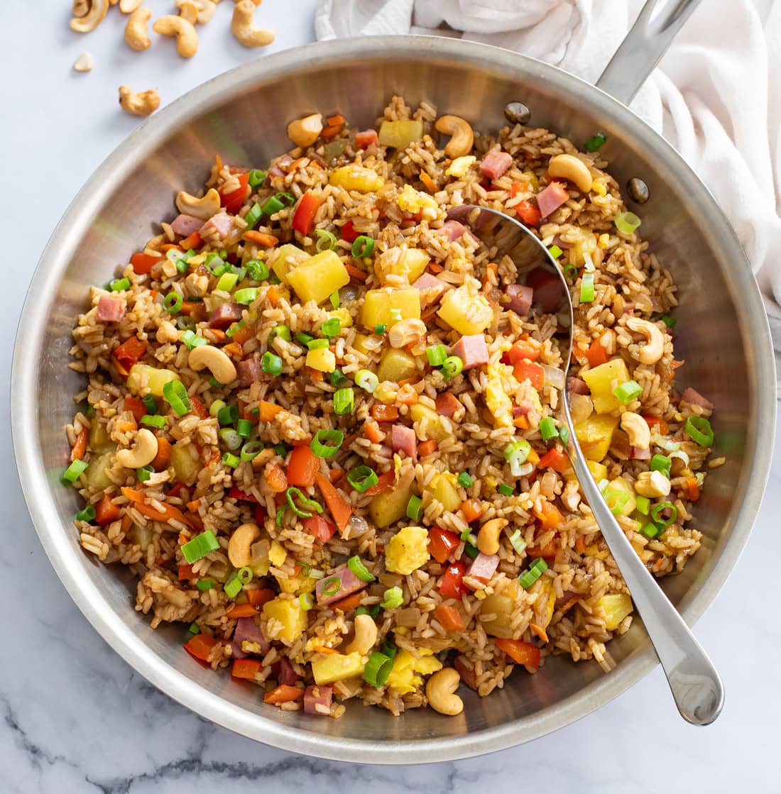 Pineapple Fried Rice in a skillet with a spoon on the side.