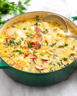 Side view of Kielbasa Potato Soup in a soup pot with a ladle in the back.