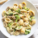 Creamy Sausage and Broccoli Pasta in a white bowl with red pepper flakes on top.