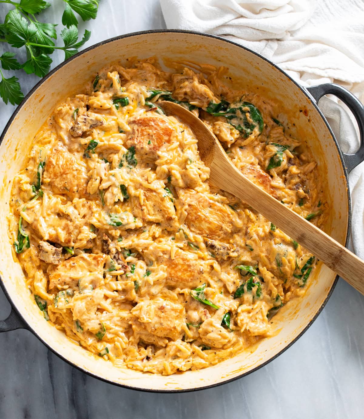 Marry Me Chicken Orzo in a skillet with a tomato cream sauce, spinach, and sun-dried tomatoes.